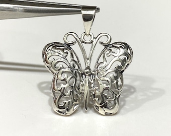 Pode incluir: Um pingente de borboleta de filigrana de prata. A borboleta tem um design delicado e intrincado com recortes em todas as asas.