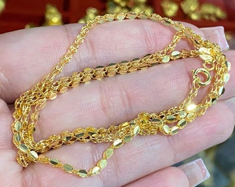May include: A gold chain necklace with a delicate oval link design. The chain is layered and appears to be made of multiple strands.