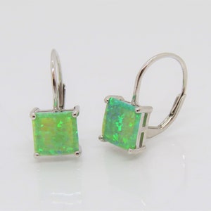 May include: A pair of silver earrings with green square-shaped opal stones. The earrings have a lever back closure.