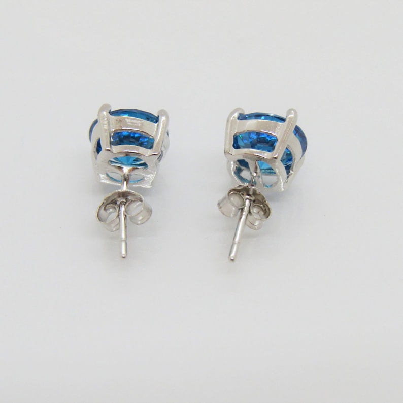 Puede incluir: Un par de pendientes de plata con una gran piedra preciosa redonda azul en cada pendiente.