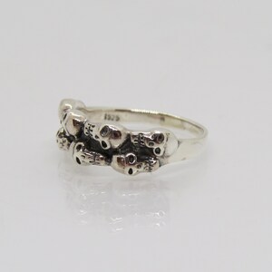 May include: Sterling silver ring with a design of multiple skulls. The ring is marked "925" on the inside band.