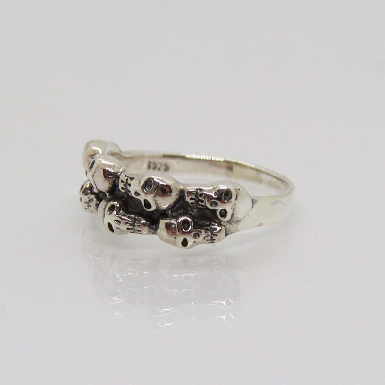 May include: Sterling silver ring with a design of multiple skulls. The ring is marked "925" on the inside band.
