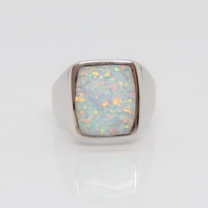 May include: A silver ring with a white opal gemstone. The opal has a shimmering, iridescent effect.