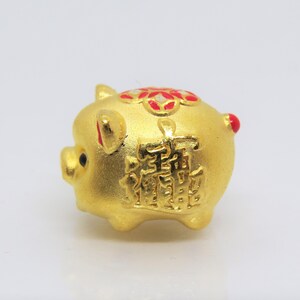 May include: A gold piggy bank with red and white accents. The piggy bank has Chinese characters on the side.