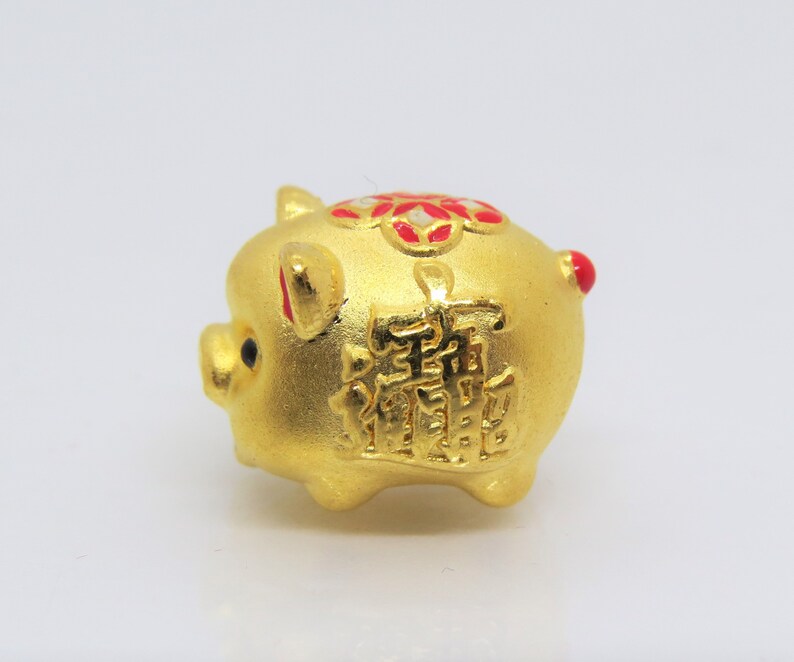 May include: A gold piggy bank with red and white accents. The piggy bank has Chinese characters on the side.