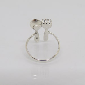 Puede incluir: Anillo de plata con dise&ntilde;o de cuchara y tenedor. El anillo est&aacute; abierto y la cuchara y el tenedor se enfrentan.