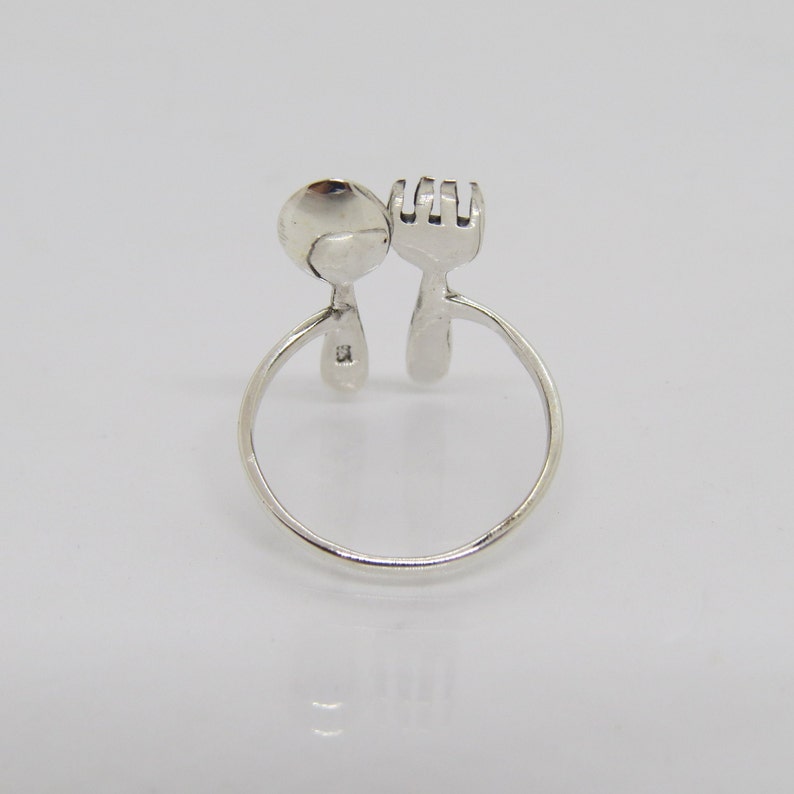 Puede incluir: Anillo de plata con dise&ntilde;o de cuchara y tenedor. El anillo est&aacute; abierto y la cuchara y el tenedor se enfrentan.
