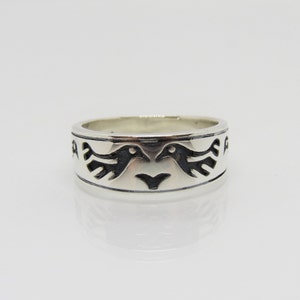 Op de afbeelding: Sterling zilveren ring met een ontwerp van twee vogels die elkaar aankijken. De vogels zijn zwart omlijnd en hebben een gestileerd ontwerp.