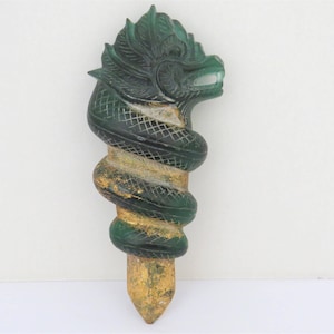 May include: A green glass dragon head sculpture with gold accents. The dragon is coiled in a spiral shape and has a detailed face.