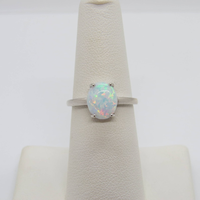 Peut inclure: Une bague en argent avec une opale blanche. L'opale pr&eacute;sente un effet iris&eacute; arc-en-ciel.