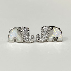 May include: A pair of silver elephant stud earrings with white opal accents and clear cubic zirconia stones.