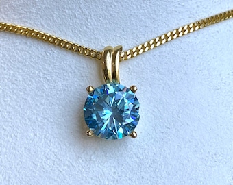 May include: A gold chain necklace with a pendant featuring a large, round, blue gemstone.