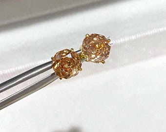 Könnte beinhalten: Ein Paar goldene Ohrringe mit einem rosafarbenen, hellbraunen Edelstein.