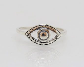 May include: A silver ring with an eye design. The eye is surrounded by a textured border.