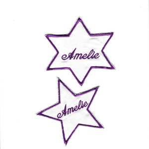 Op de afbeelding: Twee witte ster-vormige patches met paarse geborduurde randen en de naam "Amelie" in cursief schrift. De patches staan op een witte achtergrond. Deze patches kunnen worden gebruikt voor kleding of ambachten.