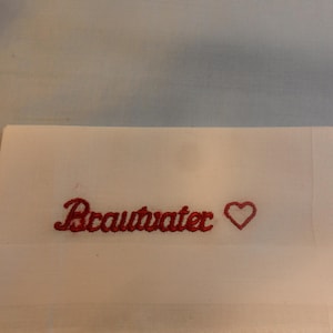 May include: White fabric with red embroidery that says "Brautvater" with a red heart next to it.