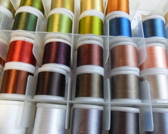 Può includere: Primo piano di una scatola di contenimento piena di bobine di filo di vari colori, tra cui marrone, verde, oro, rosso e blu.