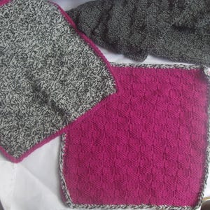 May include: Close-up of two knitted squares. One is a speckled gray and white pattern with a pink border. The other is a solid magenta color with a woven texture and a gray and white border. The squares are likely part of a larger knitted project.