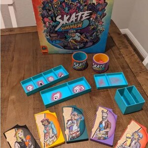 May include: A board game called "Skate Summer" with colorful illustrations of skateboarders and a city scene. The game includes a game board, cards, tokens, and dice. The game is designed for ages 8 and up.