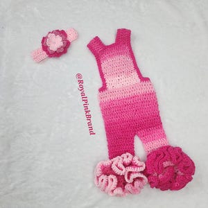 May include: Pink crocheted baby romper with a ruffled hem and a matching pink flower headband. The romper has a gradient of pink shades. The text '@RoyalPinkBrand' is visible in the image.