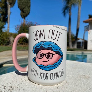 May include: White ceramic mug with a pink handle. The mug has a cartoon clam with glasses and the text "Jam Out With Your Clam Out" printed on it.