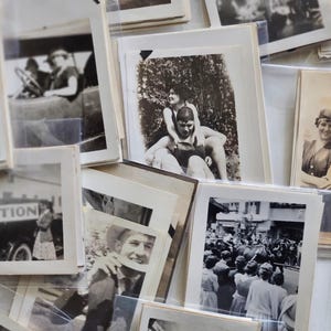 May include: A collection of vintage black and white photographs in various sizes and frames. The photos depict people, landscapes, and events from the past.