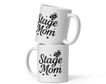 May include: Two white ceramic mugs stacked on top of each other. Both mugs have a black design that says "Stage Mom" with a spotlight graphic.