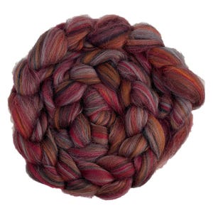 May include: A thick, braided bundle of roving wool fibre featuring a variegated colour palette of deep burgundy, burnt orange, dark charcoal, and muted grey tones, arranged in a circular, coiled pattern with a soft, fuzzy, and fibrous texture.