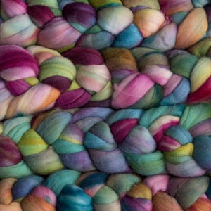 May include: A close-up of a braided yarn with a variety of colours, including pink, purple, blue, green, and yellow.