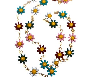 May include: A gold chain necklace with colorful enamel flower charms. The flowers are in shades of pink, red, green, blue, and yellow.