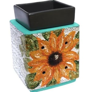 May include: A teal and silver ceramic wax warmer with a sunflower design. The warmer has a black ceramic dish on top for melting wax.