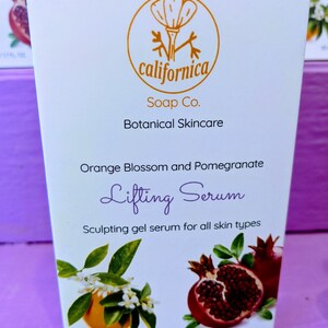 Puede incluir: Una caja blanca de cuidado de la piel bot&aacute;nico "californica Soap Co.". La caja presenta un logotipo dorado, texto e ilustraciones de flores de azahar, granadas y las palabras "Lifting Serum". El producto es un s&eacute;rum gel escultor para todo tipo de piel.