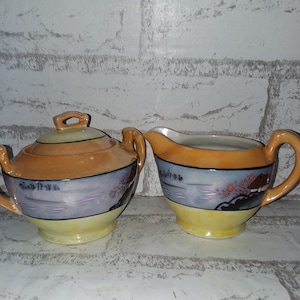 Handpainted lusterware sugar and creamer featuring a hut
