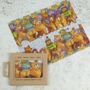 May include: A brown microfiber cleaning cloth with a repeating pattern of cartoon bears wearing colorful knitted hats and sweaters. The text "Safe & Gentle Microfiber Cloth" and "Glasses - Screens - Tablets - Camera" is printed on the cloth.