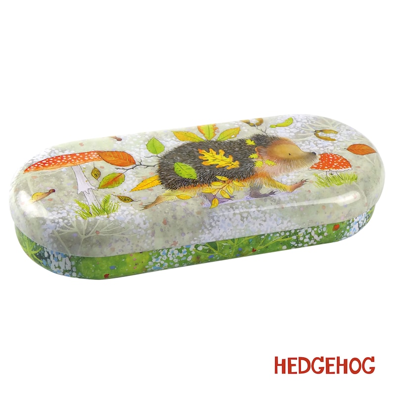 May include: A green, white, and brown metal glasses case with a hedgehog carrying autumn leaves and a mushroom on the front. The case has the word "HEDGEHOG" printed on the bottom.