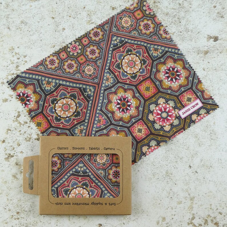 May include: A brown and gray microfiber cleaning cloth with a geometric pattern. The cloth is packaged in a brown cardboard box with the text "Soft & Absorbent Microfiber Cloth" and "Glasses, Screens, Tablets, Camera" printed on it. The cloth is labeled "Janie Crow".