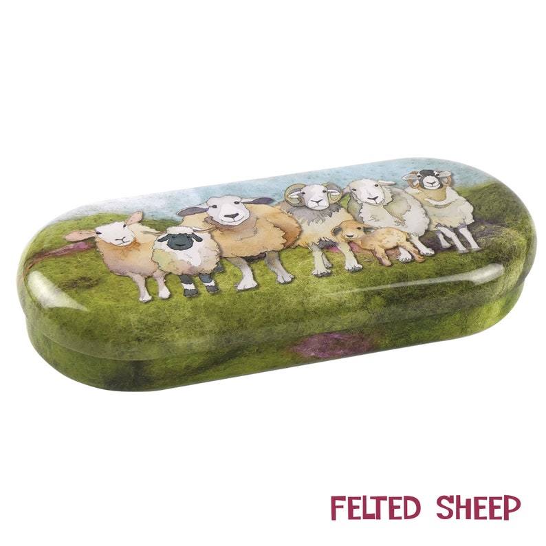 May include: A green and brown oval-shaped glasses case with a whimsical illustration of a group of sheep. The sheep are white, brown, and black with various facial expressions. The case has a felt-like texture and the words "FELTED SHEEP" are printed in red at the bottom.