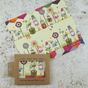 May include: A microfiber cleaning cloth with a whimsical design featuring gnomes gardening. The cloth is packaged in a brown cardboard box with the text "Glasses. Screens. Tablets. Camera" and "Soft & squidgy microfibre lens cloth" printed on it.
