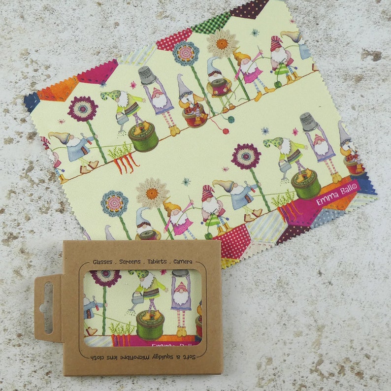 May include: A microfiber cleaning cloth with a whimsical design featuring gnomes gardening. The cloth is packaged in a brown cardboard box with the text "Glasses. Screens. Tablets. Camera" and "Soft & squidgy microfibre lens cloth" printed on it.