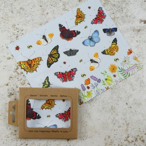 May include: A microfiber cleaning cloth with a blue background and a colorful butterfly pattern. The cloth is packaged in a brown cardboard box with the text "Soft & Smooth Microfibre Lens Cloth" and "Glasses - Screens - Tablets - Camera" printed on it.