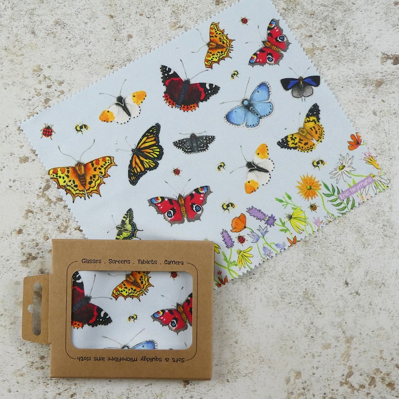 May include: A microfiber cleaning cloth with a blue background and a colorful butterfly pattern. The cloth is packaged in a brown cardboard box with the text "Soft & Smooth Microfibre Lens Cloth" and "Glasses - Screens - Tablets - Camera" printed on it.