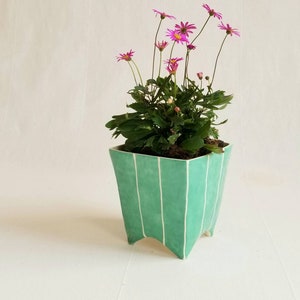 Small square ceramic planter with 4 pointed feet. Shown in jade green, potted with plant