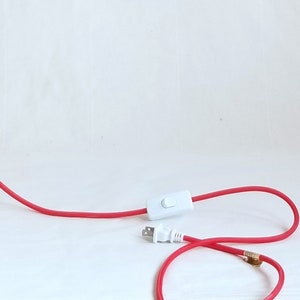 detail of red plugin cord showing white thumb switch and plug