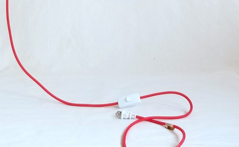 detail of red plugin cord showing white thumb switch and plug