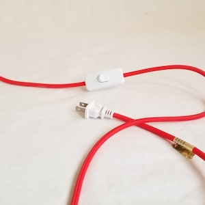 Detail of red plugin cord showing thumb switch and plug