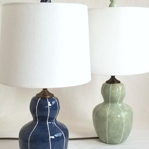 2 Bedside table lamps in dark blue & Celadon with thin white stripes. Topped with white linen shades and matching finials