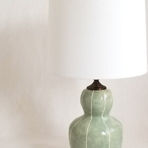 Small table lamp in celadon with thin white stripes. Topped with a white linen shade and matching finial