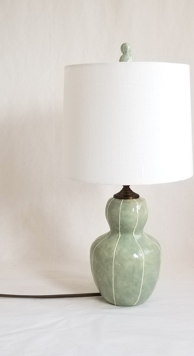 Small table lamp in celadon with thin white stripes. Topped with a white linen shade and matching finial