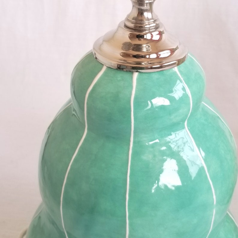 Detail of handmade jade green ceramic lamp with thin, raised white stripes