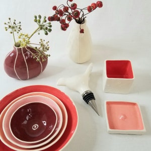 small, handmade ceramic bowls in red, peach, pink& maroon.
Shown with bud vases, lidded box and bird wine stopper.